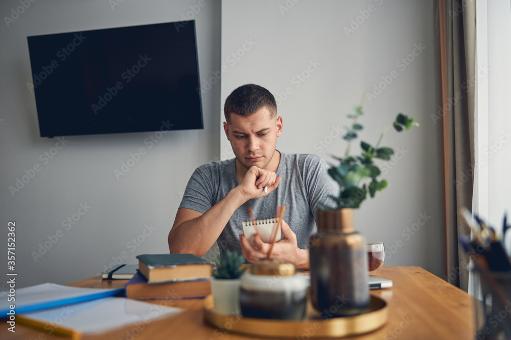 Attractive young man looking serious while reading Attractive young man looking serious while reading