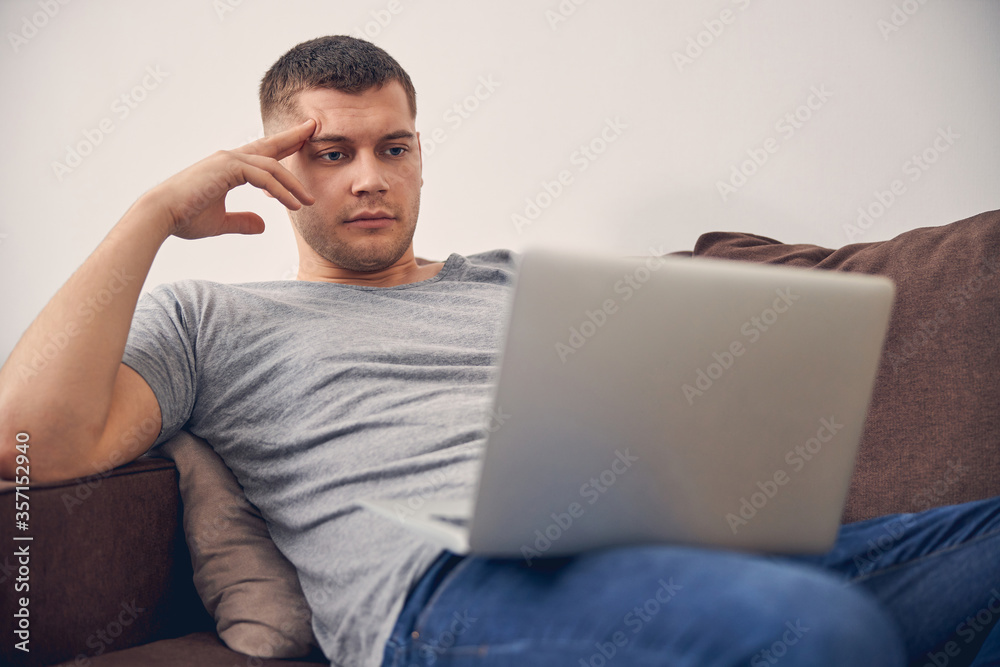 Concentrated young male staying at home with laptop Concentrated young male staying at home with laptop