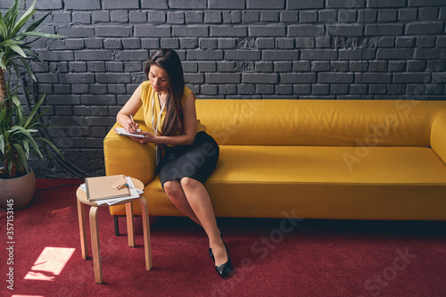 Attractive young woman sitting on sofa in hall
