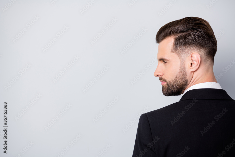 Back rear spine profile side photo of stylish worker man look copyspace listen to his collar wear black classy suit isolated over grey color background Back rear spine profile side photo of stylish worker man look copyspace listen to his collar wear black classy suit isolated over grey color background