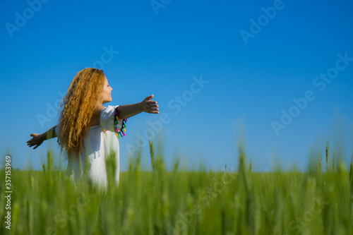 Summer holidays vacation of carefree beautiful long haired woman runs on summer sunny field. Positive happy girl in white dress walking alone on sunny yard.Freedom or happiness concept.Social distance