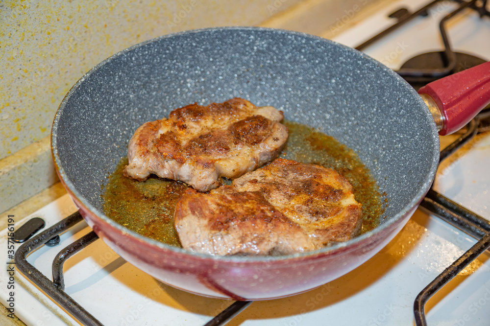 Juicy appetizing steaks from fat pork fried in a pan with olive oil Juicy appetizing steaks from fat pork fried in a pan with olive oil
