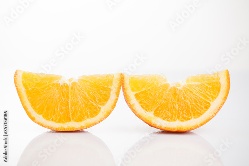Two slices of sliced       orange on a white background with reflection at the bottom. Isolated photo of citrus.