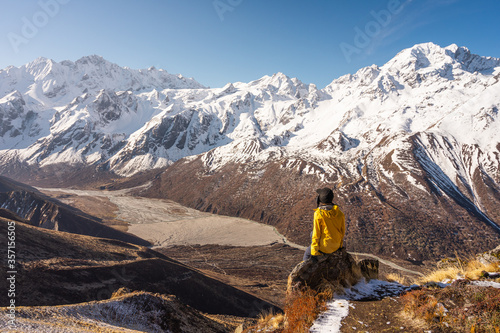 A trekker sitting on top of Kyanjo Ri view point and enjoying landscape of Langtang valley. Himalaya mountains range in Nepal