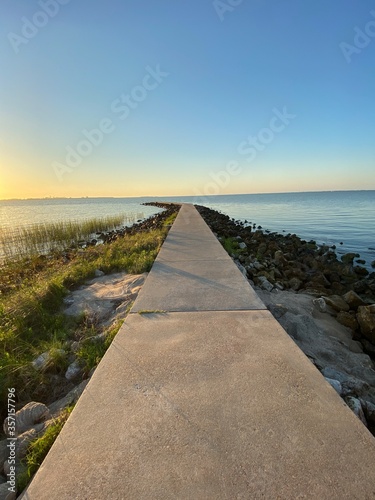 Sunrise concrete pier over water