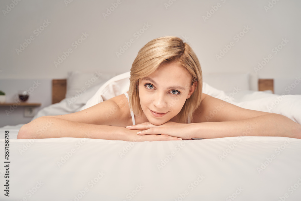 Smiling lovely lady relaxing in a bedroom Smiling lovely lady relaxing in a bedroom