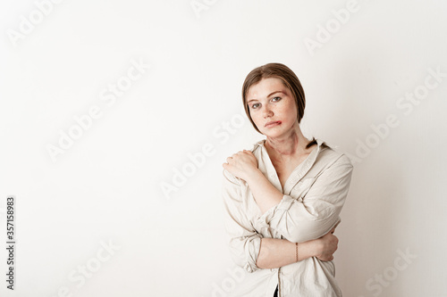 a victim of cruel domestic violence stands on a white isolated background, a girl with bruised face and bruises on her neck