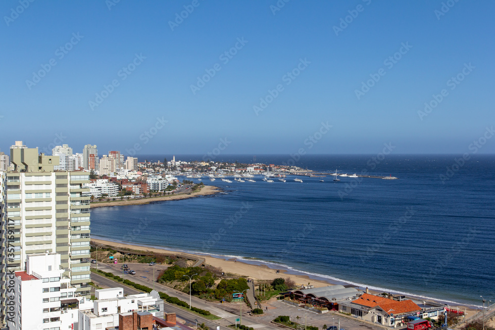 Balcony view of the coastline at a holiday resort in Punta Del Este, Uruguay: the quiet beach and boats in the harbour at the background on a clear sunny day of winter.