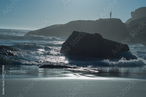 Sunset on Llandudno Beach in Cape Town, South Africa. The setting sun reflects off the ocean catching the wind-driven spray from the waves at Llandudno beach.