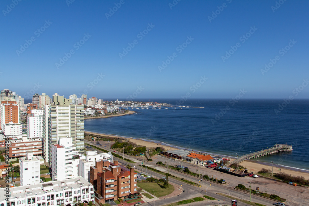 Balcony view of the beautiful coastline at a holiday resort in Punta Del Este, Uruguay: the quiet empty beach, the calm water and boats in the harbor at the background on a clear sunny day of winter.
