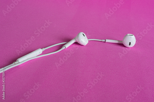 white headphones lie on a pink background