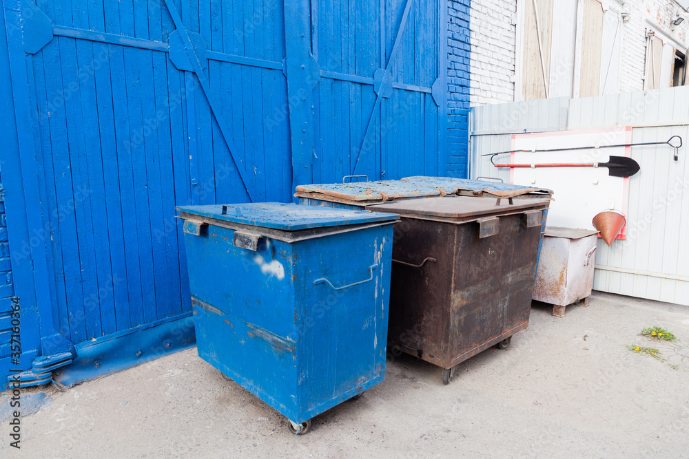 Garbage containers near a blue brick wall Garbage containers near a blue brick wall