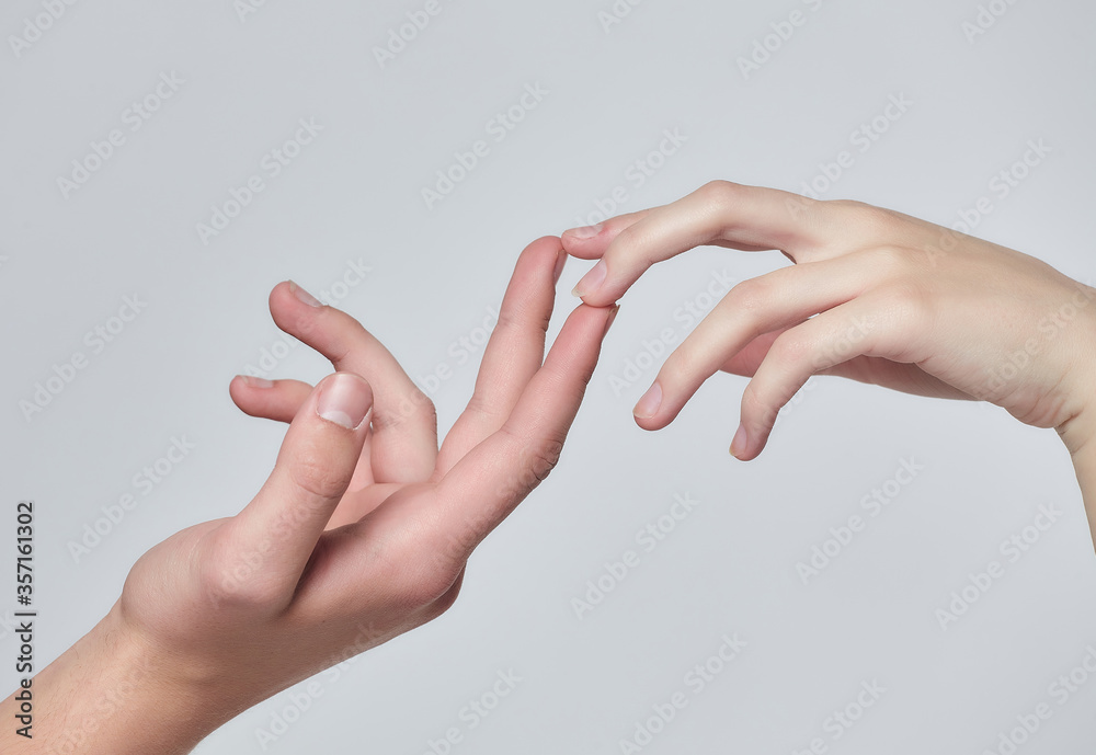 the hands of a young boy and a young girl reach out to each other. white background