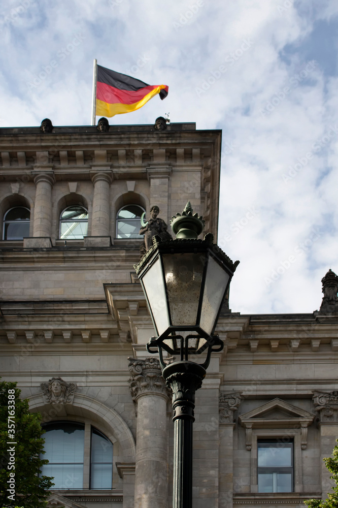 Obraz premium Lampa uliczna z budynkiem Reichstagu i niemiecką flagą w tle w Berlinie