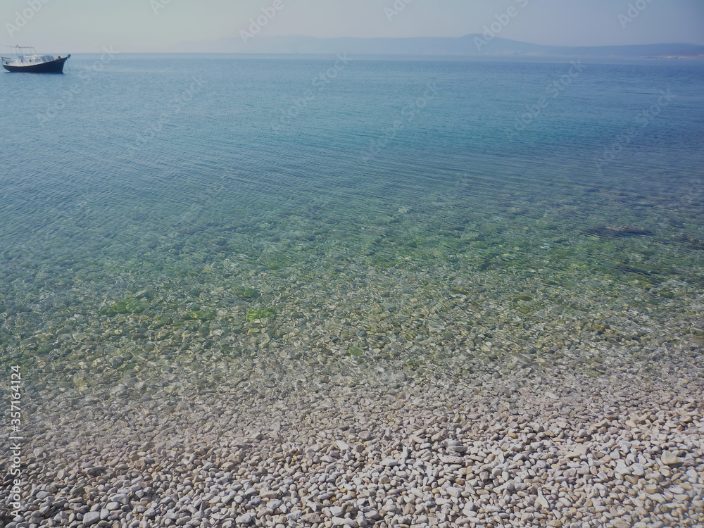 View on clear calm turquoise sea with a boat and without people on a sunny summer day View on clear calm turquoise sea with a boat and without people on a sunny summer day