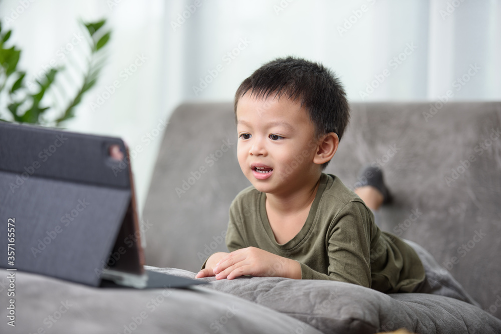 Asian boy with a cute face and good temper is looking and smiling at the camera in front of the tablet. While talking to friends via video call. Asian boy with a cute face and good temper is looking and smiling at the camera in front of the tablet. While talking to friends via video call.
