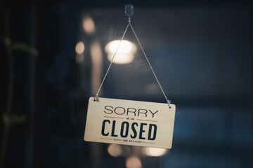 sorry we are closed sign hanging outside a restaurant, store, office or other. Closed sign in a shop showroom with reflections bokeh.