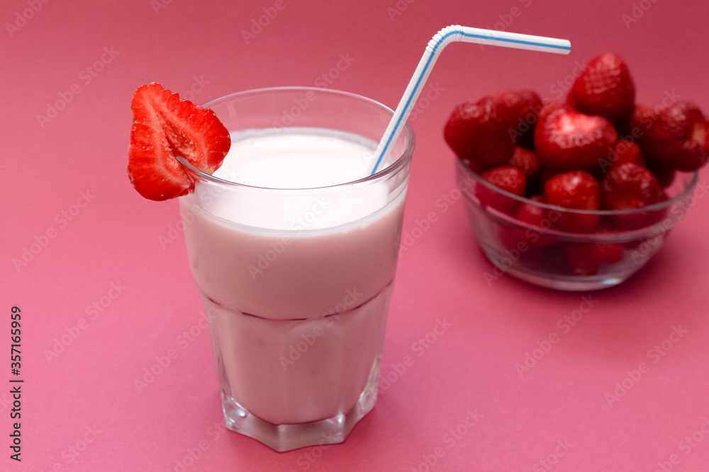 Strawberry smoothie in glass with sliced berries and straw on light, soft, pink background. Strawberry smoothie in glass with sliced berries and straw on light, soft, pink background.