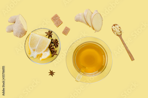 Tea in glass Cup with ginger root pieces isolated on yellow background