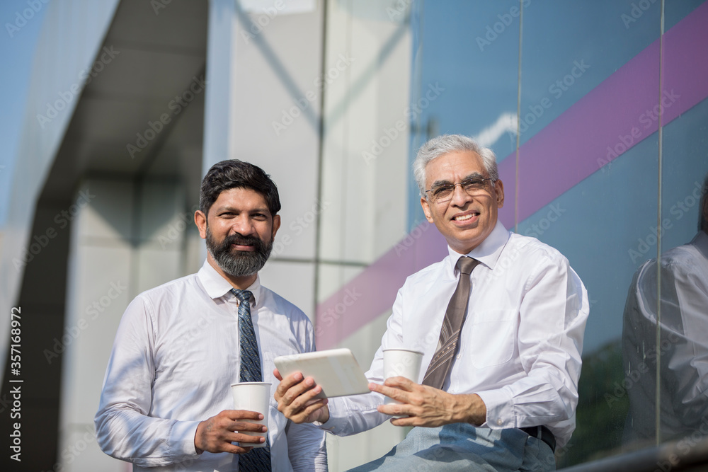 Businessman using a digital tablet to discuss information with senior leadership Businessman using a digital tablet to discuss information with senior leadership