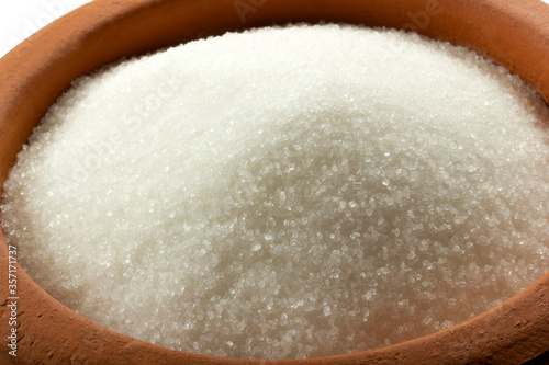 Granulated sugar in bowl. Crystals of refined table sugar. Sweet soluble carbohydrates. Sucrose, disaccharide of glucose and fructose.