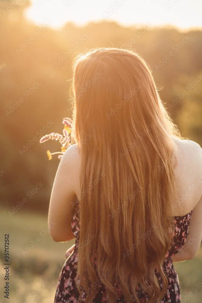 romantic girl with bouquet of wildflowers on meadow, young woman with long hair in dress walking on nature,summer tender photo in village