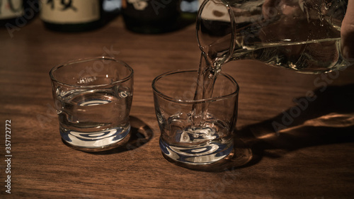 Pours sake, japenese rice wine into a glass.
