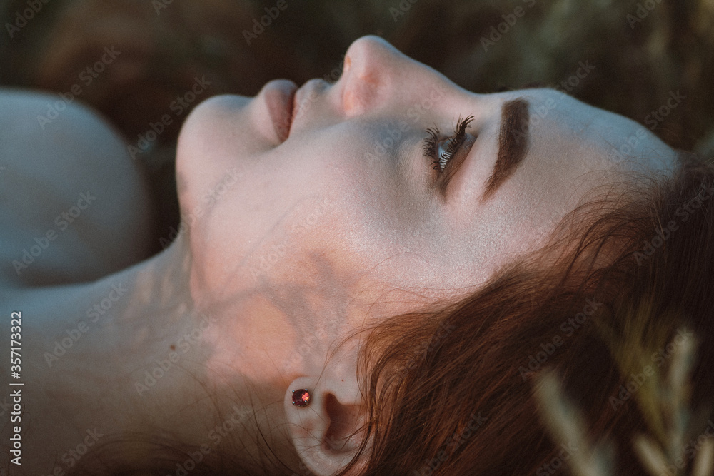 close-up face of beautiful girl lying on the grass , young woman with long hair on nature,summer tender photo in village close-up face of beautiful girl lying on the grass , young woman with long hair on nature,summer tender photo in village