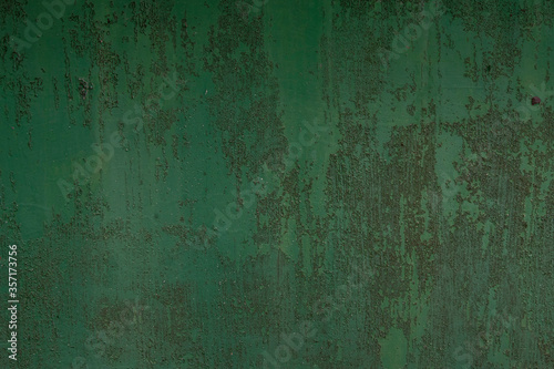 the surface of the old metal, pitted with rust, covered in old green paint