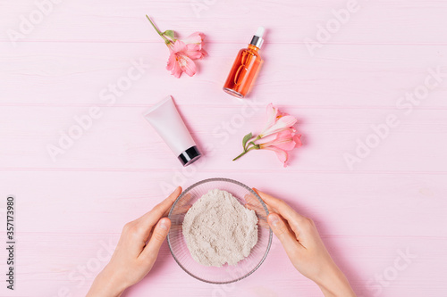 Top view female hands holding bowl of cosmetic clay powder