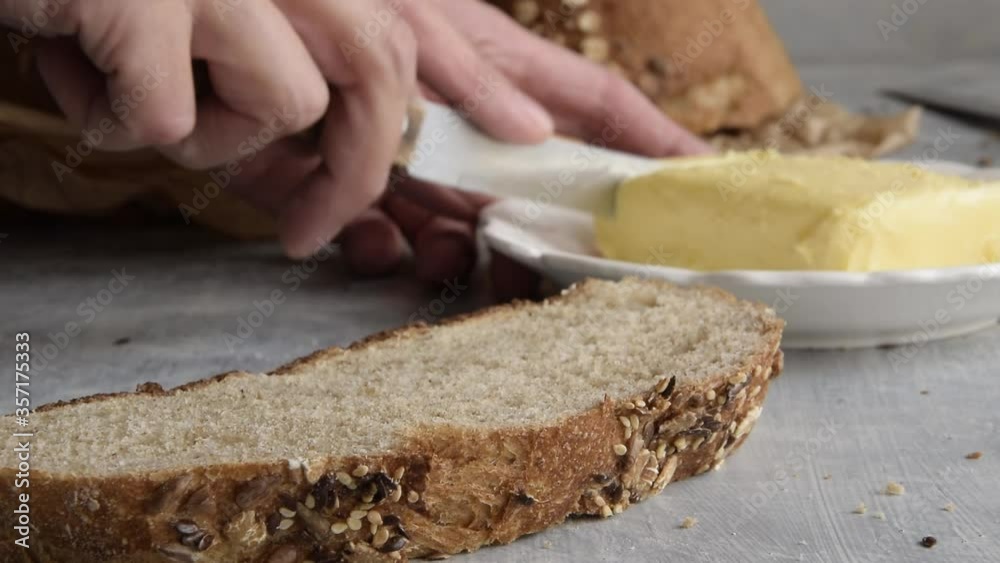 Spread fresh butter on sliced whole oat bread. Healthy eating concept
Spread fresh butter on sliced whole oat bread. Healthy eating concept