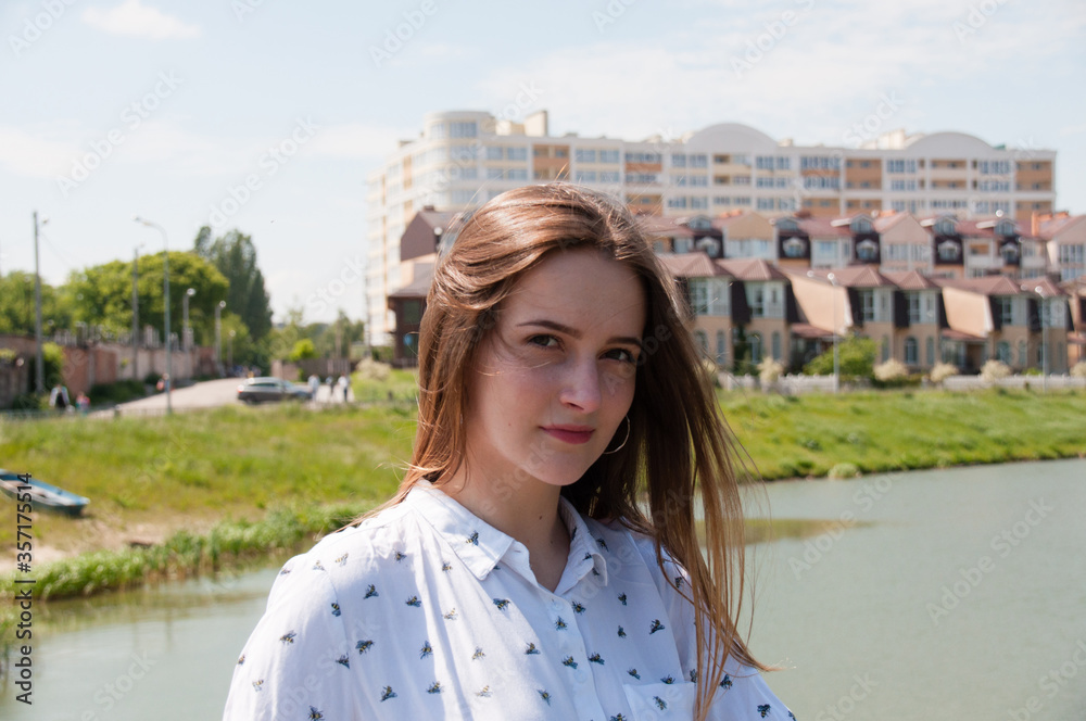 Sunny, summer portrait of a beautiful girl in a white blouse, on the river bank in the city of Chernihiv