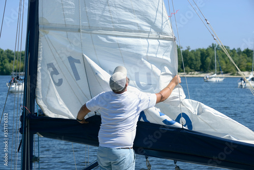 Canvas-taulu Yachtsman setting sail of a yacht before race