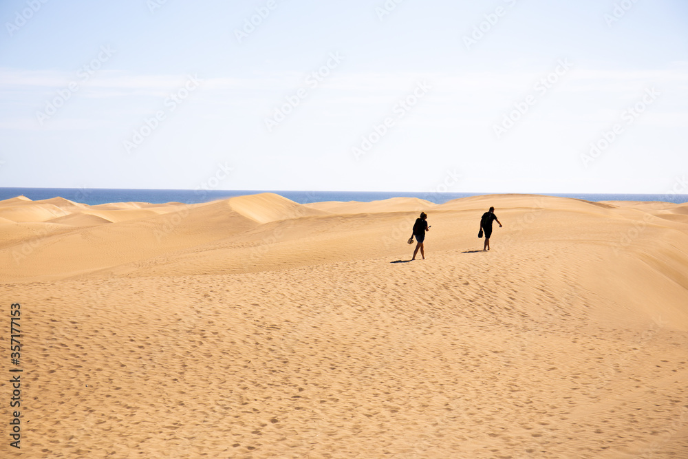 people walking on sand hills near Atlantic ocean against clear blue sky in Maspalomas, Gran Canaria people walking on sand hills near Atlantic ocean against clear blue sky in Maspalomas, Gran Canaria