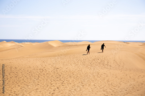 people walking on sand hills near Atlantic ocean against clear blue sky in Maspalomas  Gran Canaria