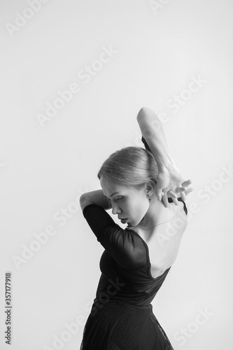 Black and white portrait of beautiful young woman with fair hair gymnastics training calilisthenics exercise on white studio background. photo