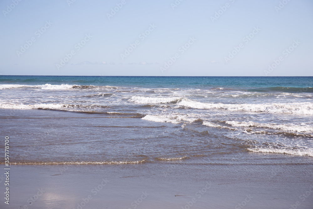Atlantic ocean with waves against clear blue sky at sunny day in Maspalomas, Gran Canaria