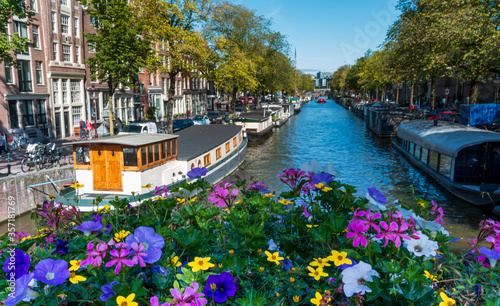 Photography Gracht  Canal in amsterdam netherlands with boats and flowers on a bridge