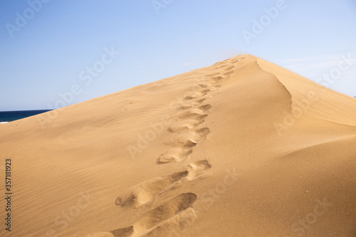 footsteps on sand dune against clear blue sky in Maspalomas, Gran Canaria