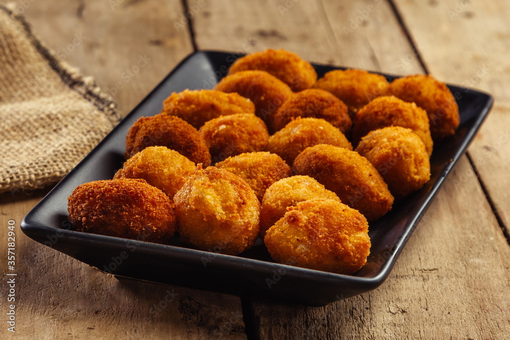 Croquettes in black plate on wooden table Croquettes in black plate on wooden table
