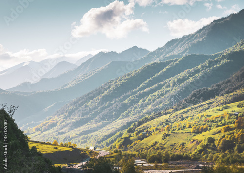 Lorry truck travels in the mountains with scenic landscape. Shipment and delivery in caucasus. Travelling in Kazbegi national park in Autumn.