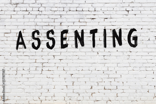 Word assenting painted on white brick wall