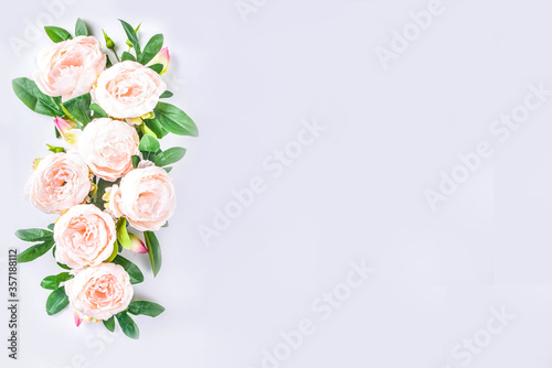 Floral peonies arrangement . Artificial tender white pinkish peony flower with leaves, flat composition on a light background. top view place for text