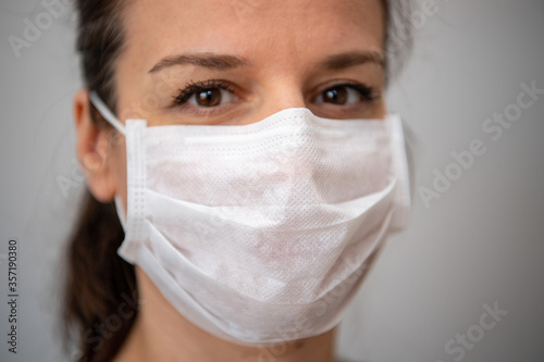 Head shot portrait attractive woman looking at camera wear medical white colour face mask