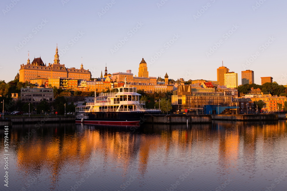 Upper and lower old town skyline seen from the Louise Basin during a golden hour dawn with moored excursion boat in the foreground, Quebec City, Quebec, Canada 