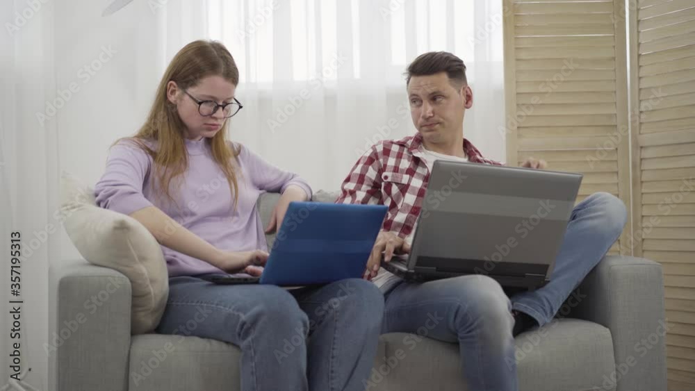 Nervous redhead woman yelling at brunette young man showing her his laptop screen. Portrait of dissatisfied Caucasian girlfriend arguing with boyfriend at home as surfing Internet. Lifestyle, conflict Nervous redhead woman yelling at brunette young man showing her his laptop screen. Portrait of dissatisfied Caucasian girlfriend arguing with boyfriend at home as surfing Internet. Lifestyle, conflict