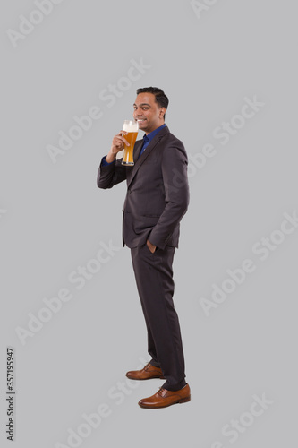 Businessman Drinking Beer from Glass. Indian Business man Standing Full Length with Beer in Hand