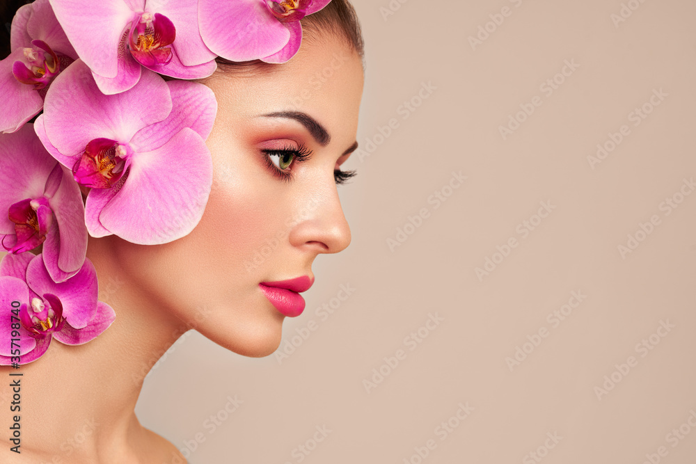 Portrait of beautiful young woman with orchid. Brunette woman with luxury makeup. Perfect skin. Eyelashes. Cosmetic eyeshadow. Purple flowers Portrait of beautiful young woman with orchid. Brunette woman with luxury makeup. Perfect skin. Eyelashes. Cosmetic eyeshadow. Purple flowers