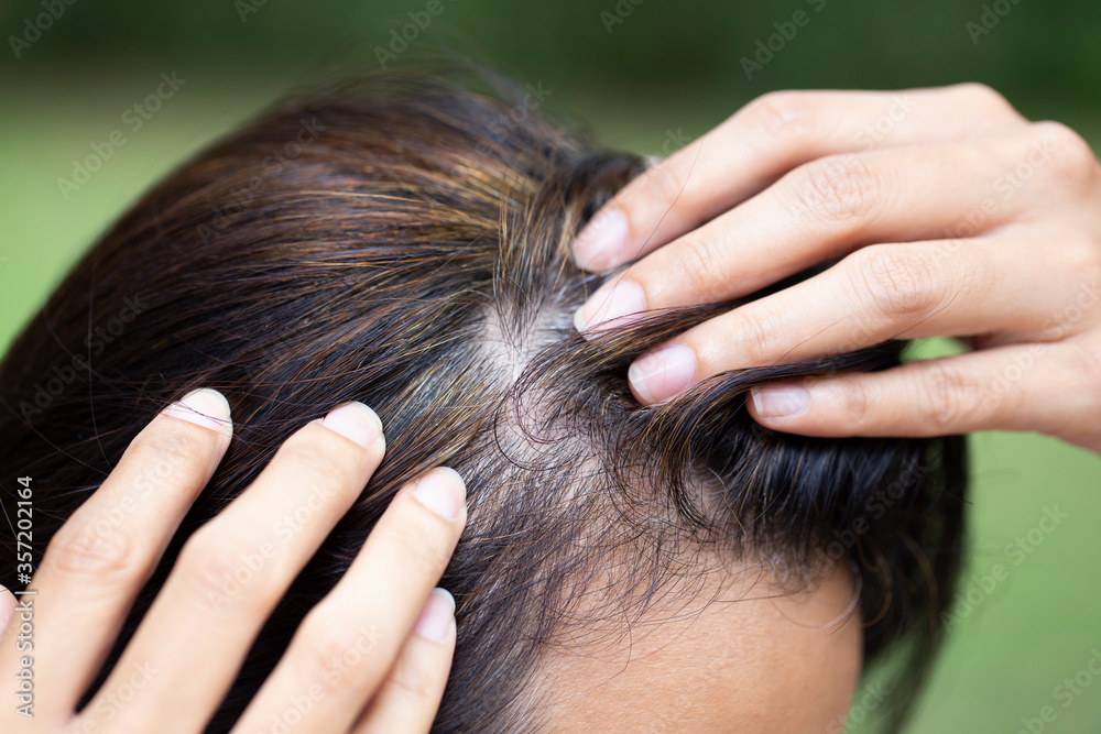 Naklejka premium Young woman shows her gray hair roots