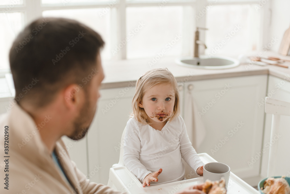 Young cute family with little daughter have breakfast at home in the kitchen. Young cute family with little daughter have breakfast at home in the kitchen.